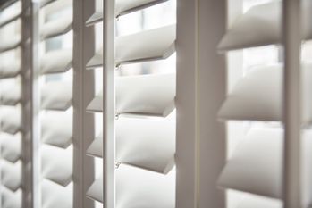 close up of full height silk white shutters in bedroom