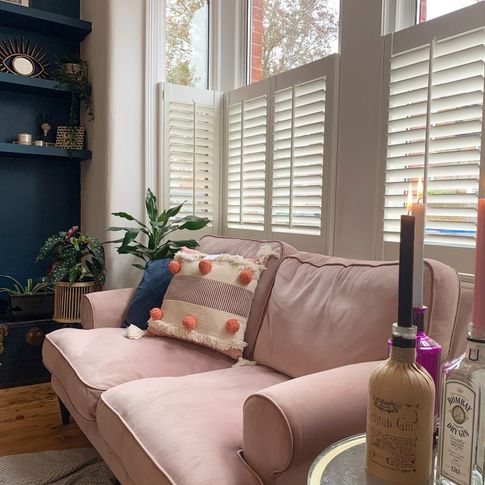 Decorators white cafe shutters in living room with pink sofa