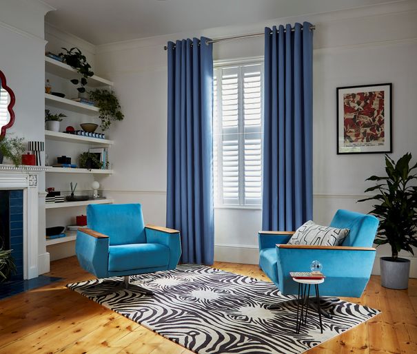 Faso cornflower blue eyelet curtains paired with white shutters in living room