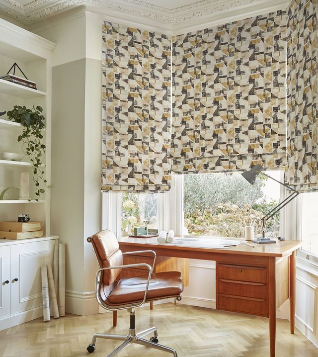 Fraction amber geometric roman blinds on bay window in home office