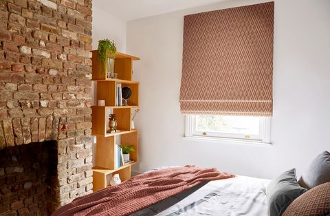 Zircon spice patterned roman blind in small bedroom with exposed brick and bookshelf