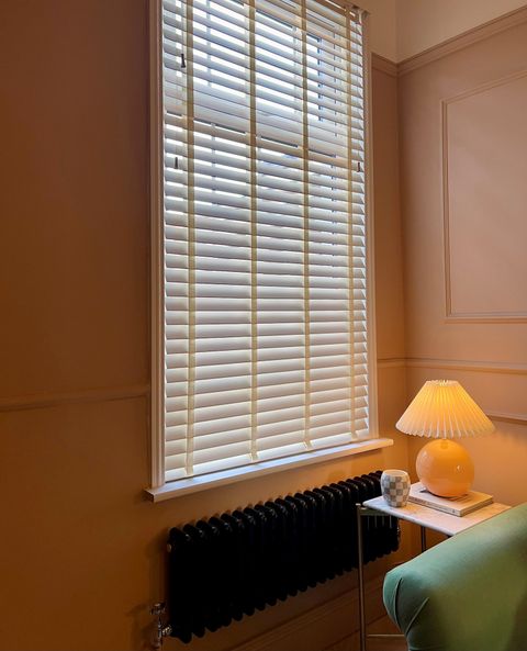 White faux wood venetian blinds with pearl tape in green living room