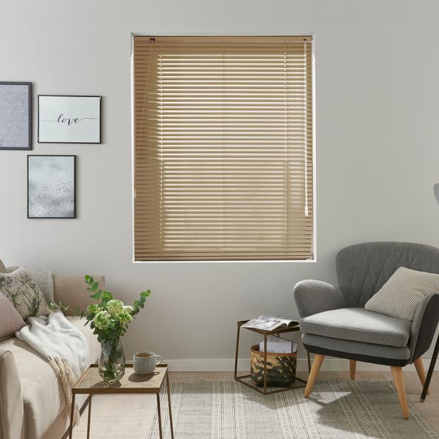 Natural taupe metal venetian blinds in beige living room with grey armchair