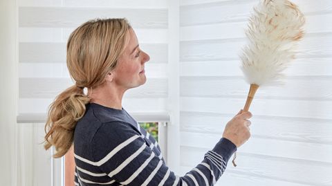 woman cleaning white day & night roller blinds with duster
