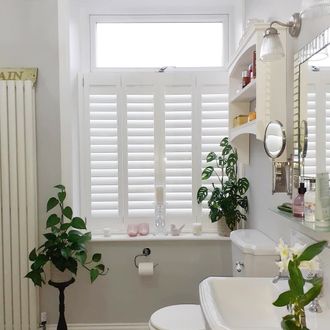 Extra white cafe style shutters on small window in bathroom