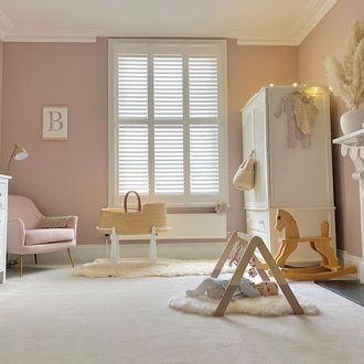 full height white shutters in pastel themed nursery with rocking horse in the middle of the room