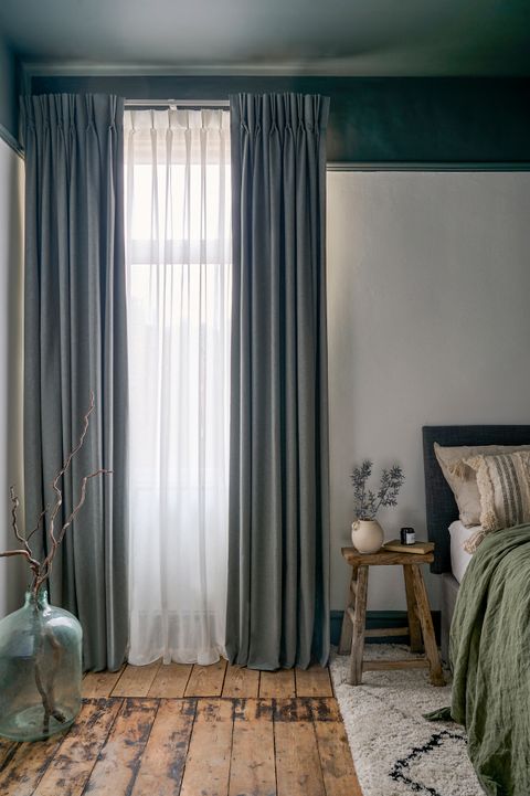 grey floor length curtains paired with cream voile curtains in a cosy neutral themed bedroom