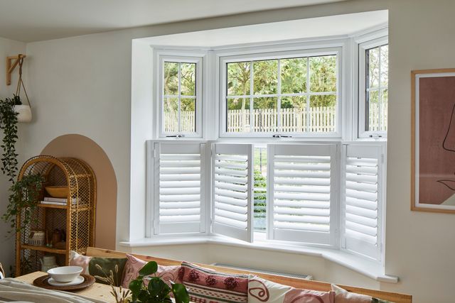 half open white cafe shutters on a bay window in a dining room
