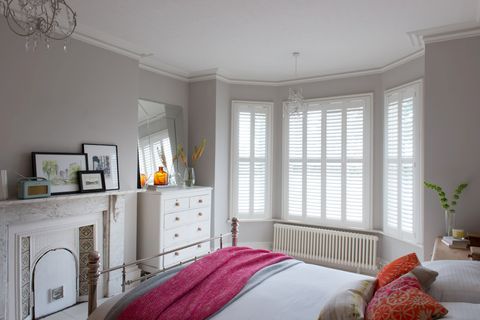 white wooden shutters on a bay window in a spacious bedroom