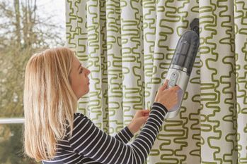 woman cleaning curtains with steamer