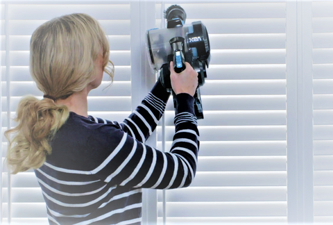 woman cleaning shutters with vacuum