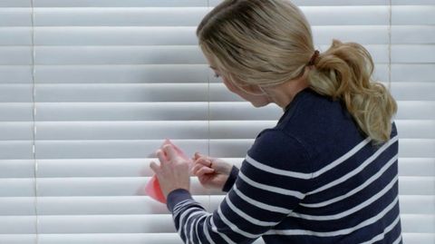 woman cleaning wooden blinds