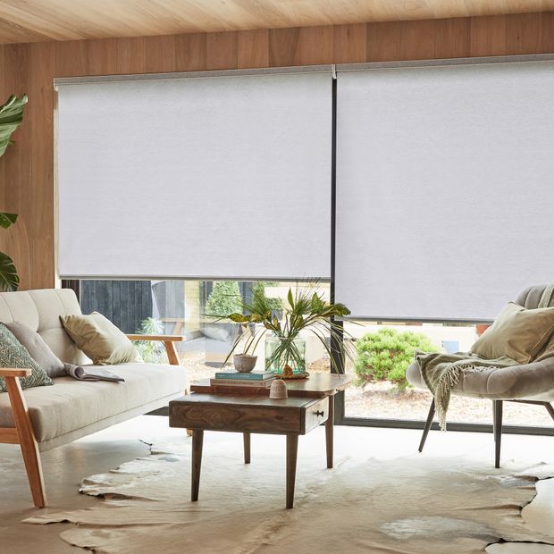 Dual compose shadow light grey roller blinds on large patio doors in cosy living room