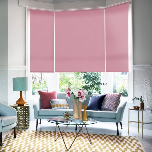 Set of three bright pink roller blinds on bay window in living room