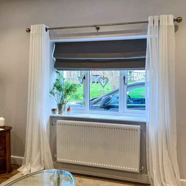 dark grey roman blinds paired with white voiles on living room window