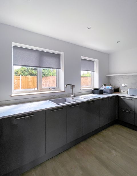 plain textured light grey roller blinds on two kitchen windows above sink and countertops
