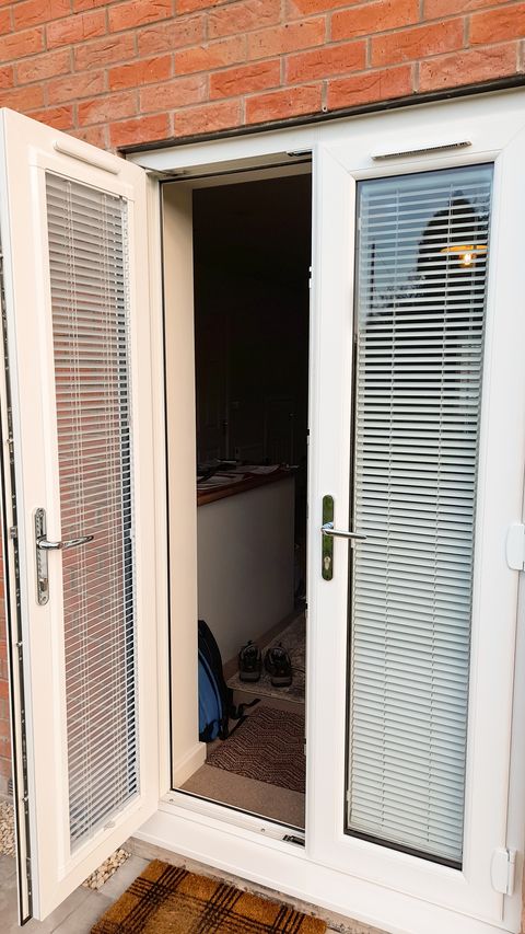 perfect fit white metal venetian blinds on french doors leading out to decking area