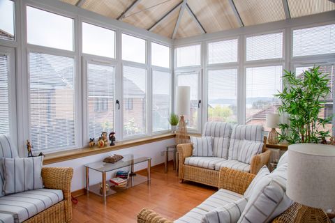 white metal venetian blinds on side windows in large conservatory with rattan furniture
