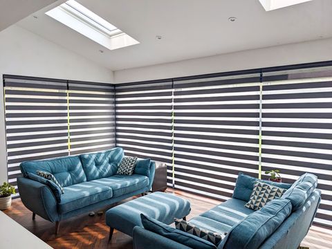 black dimout day and night blinds in living room with blue sofas