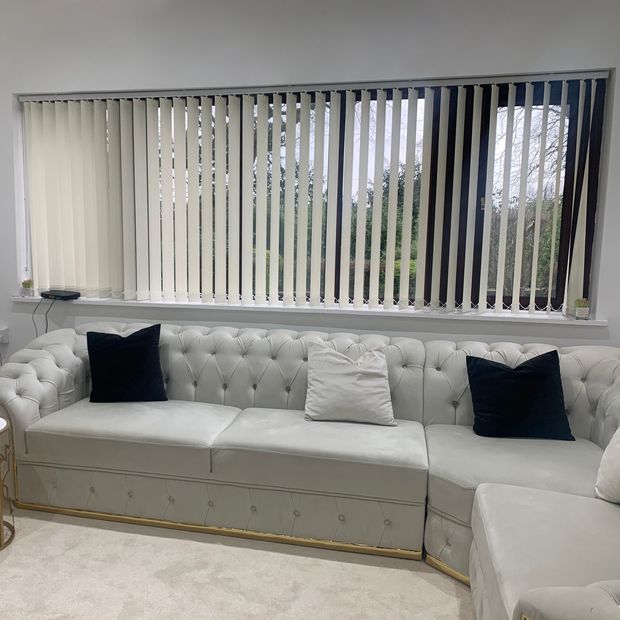 light cream vertical blinds on long window in living room with white leather sofas