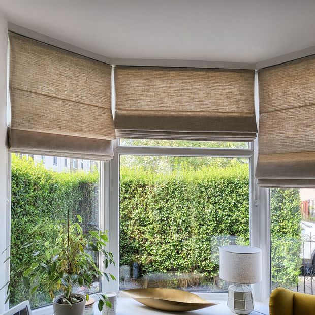 light brown slightly sheer roman blinds on bay window in living room
