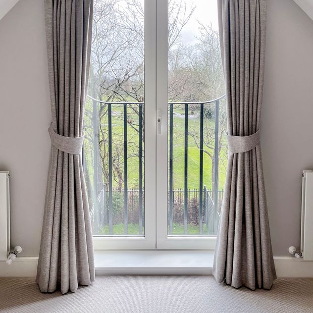 cream textured floor length curtains on french doors with matching tie backs
