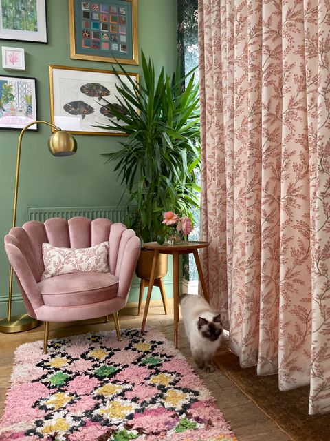floral pink floor length curtains in stylish living room with scalloped pink chair, floral rug and sage green walls