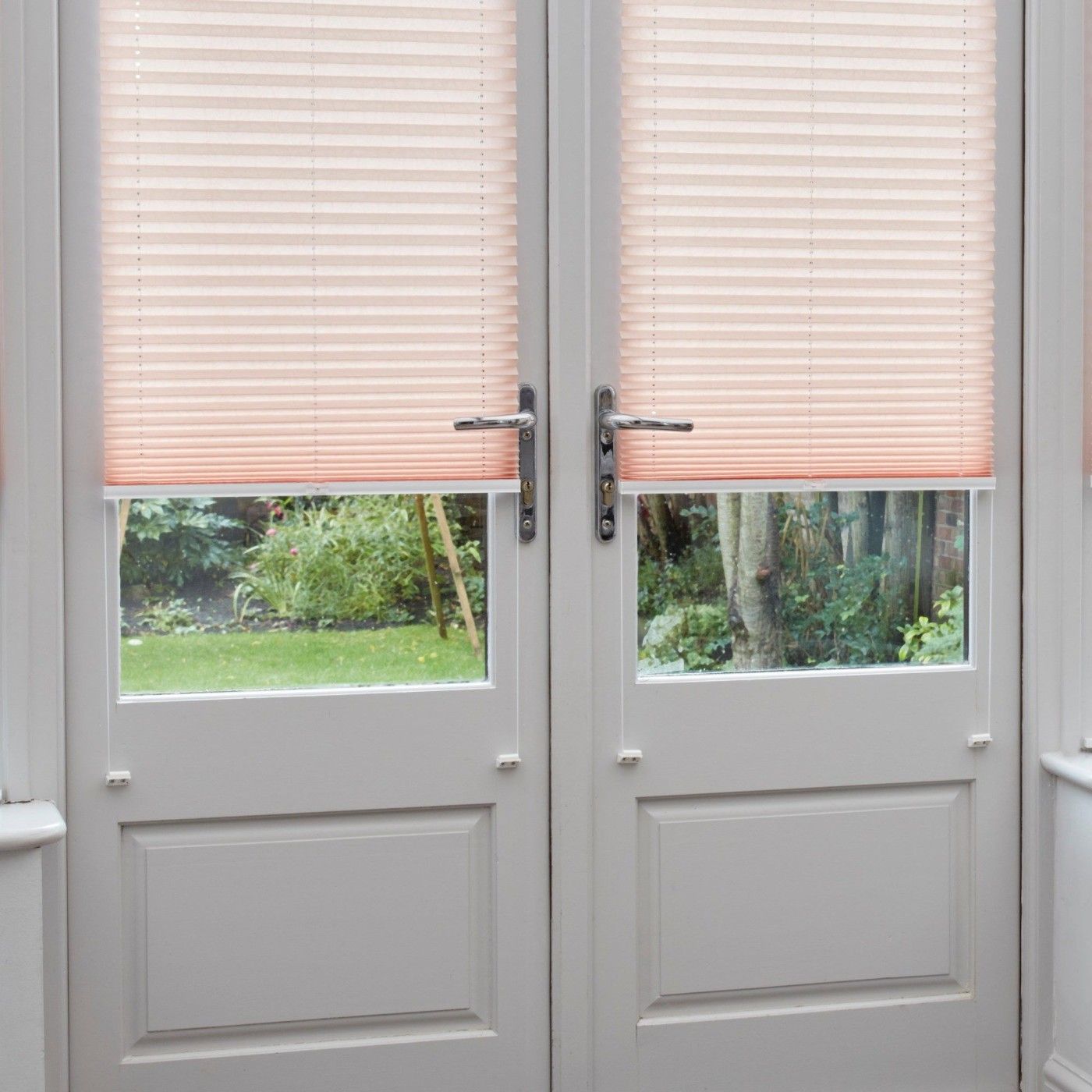 close up of light pink pleated blinds on closed french doors in conservatory