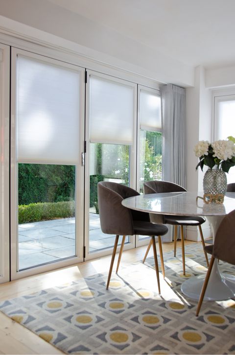 white honeycomb pleated blinds paired with silver voiles on bi-fold doors in dining room