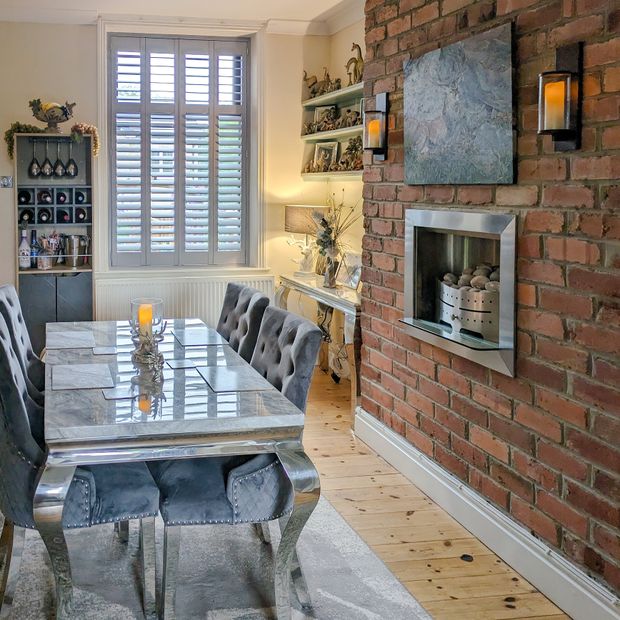 grey shutters in classically styled kitchen/diner, with grey furnishings and exposed brick walls