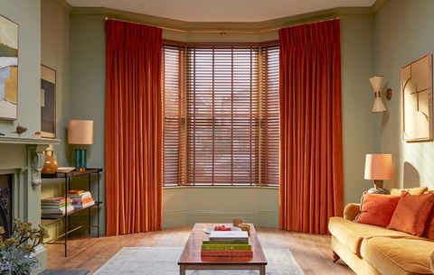 burnt orange floor length curtains on wide bay window paired with wooden blinds