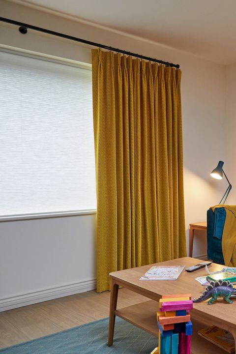 wave Sulphur pinch pleat curtains paired with pleated blinds in slightly cluttered living room 
