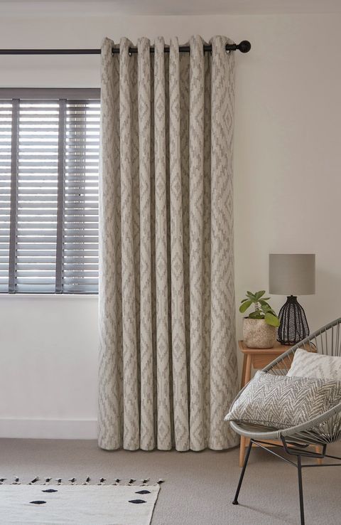 cream geometric patterned floor length curtains paired with grey faux wooden blinds on bedroom window