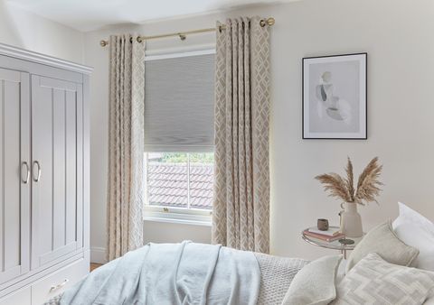 cream geometric curtains paired with grey pleated blinds in bedroom
