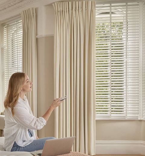 white wooden blinds paired with cream curtains in elegant bedroom