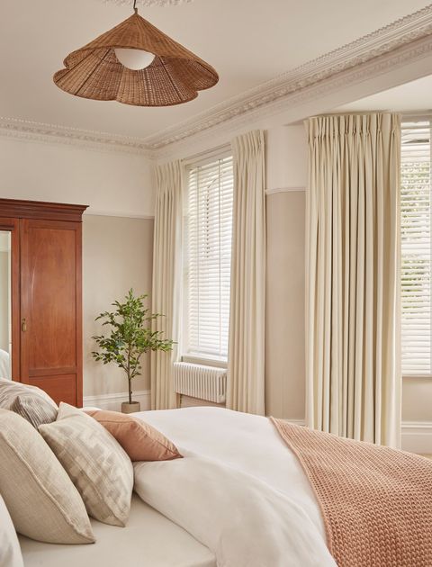 white wooden blinds paired with cream curtains in elegant bedroom