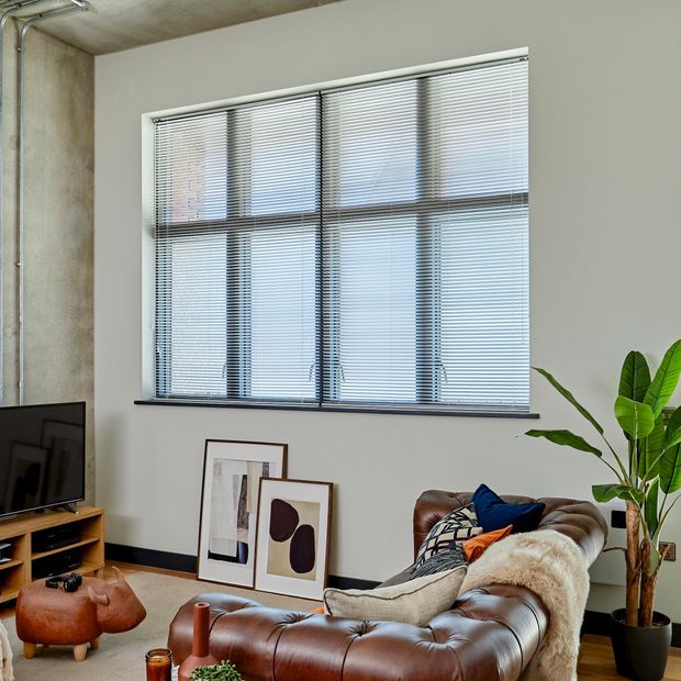grey metal venetian blinds on large window in apartment living room with industrial vibes