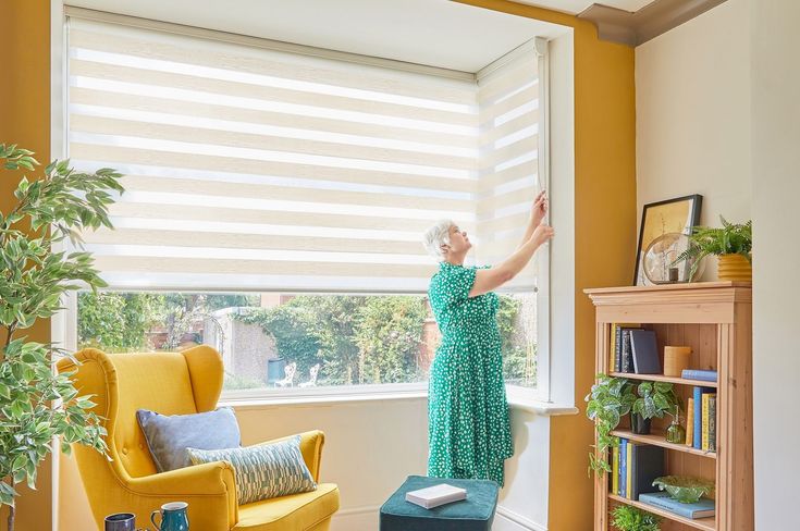 cream day and night blinds on box bay window with woman in green dress opening them