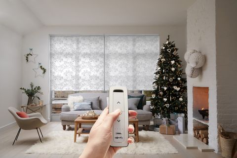 silver and white patterned roller blinds in christmas living room with person using a remote control to control the blinds