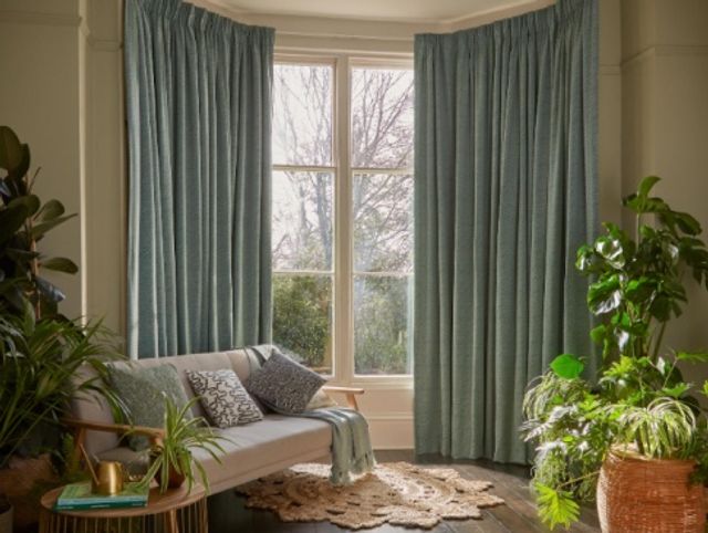 green curtains on large bay windows in living room