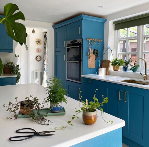 deep green roller blind on small window above dark blue themed kitchen