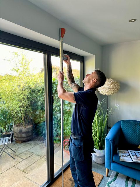 Hillarys advisor in home taking measurements of a window