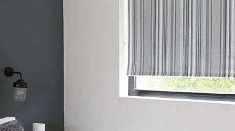 Roller blinds in Lester Silver hung in stylish grey bedroom