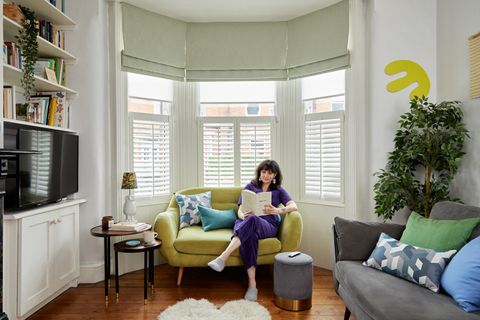 Green curtains and cafe style shutters covering a large bay window