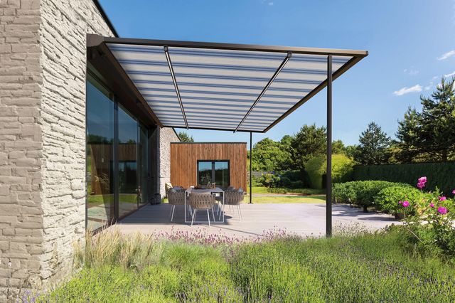 Garden shot showing a blue and white striped pergola awning extended over a patio with modern table and chairs underneath.