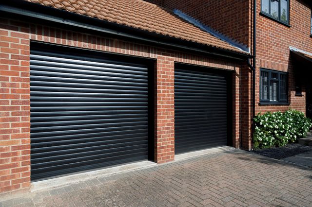 Close up of modern brick property with attached double garage with garage doors in dark grey.