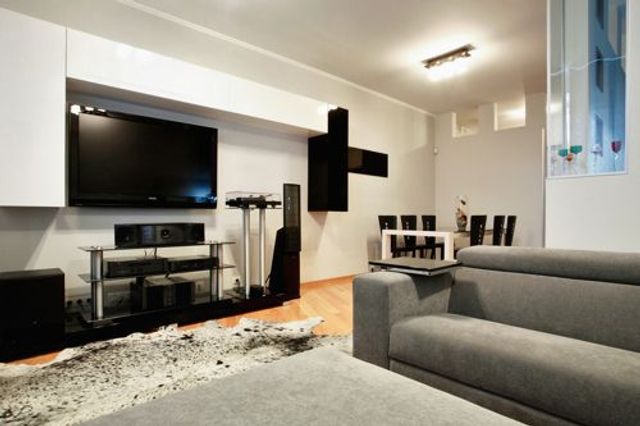 Home den with sofas and tv entertainment systems, speakers, shelving for consoles.