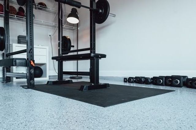 A home gym with bench press, barbells and weights.