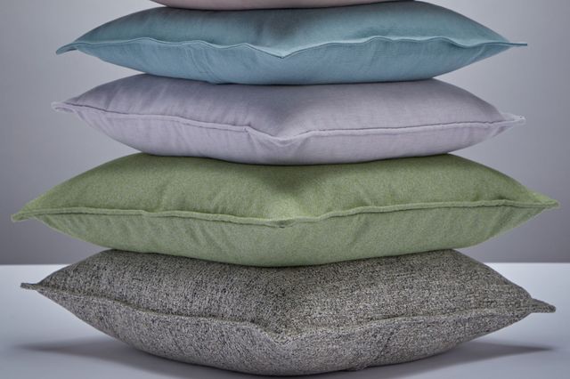 A stack of six cushions, from the bottom up in speckled brown, sage, lilac, aqua, pink and speckled blue.