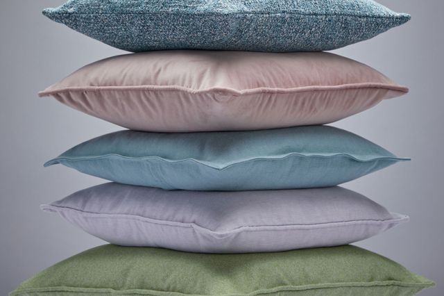 A stack of six cushions, from the bottom up in speckled brown, sage, lilac, aqua, pink and speckled blue.